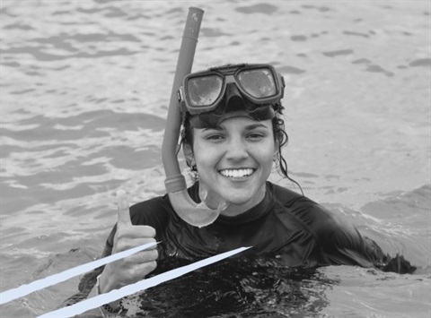 Image shows a black and white rendered photo of a teenage girl in professional snorkelling gear giving a thumbs up.